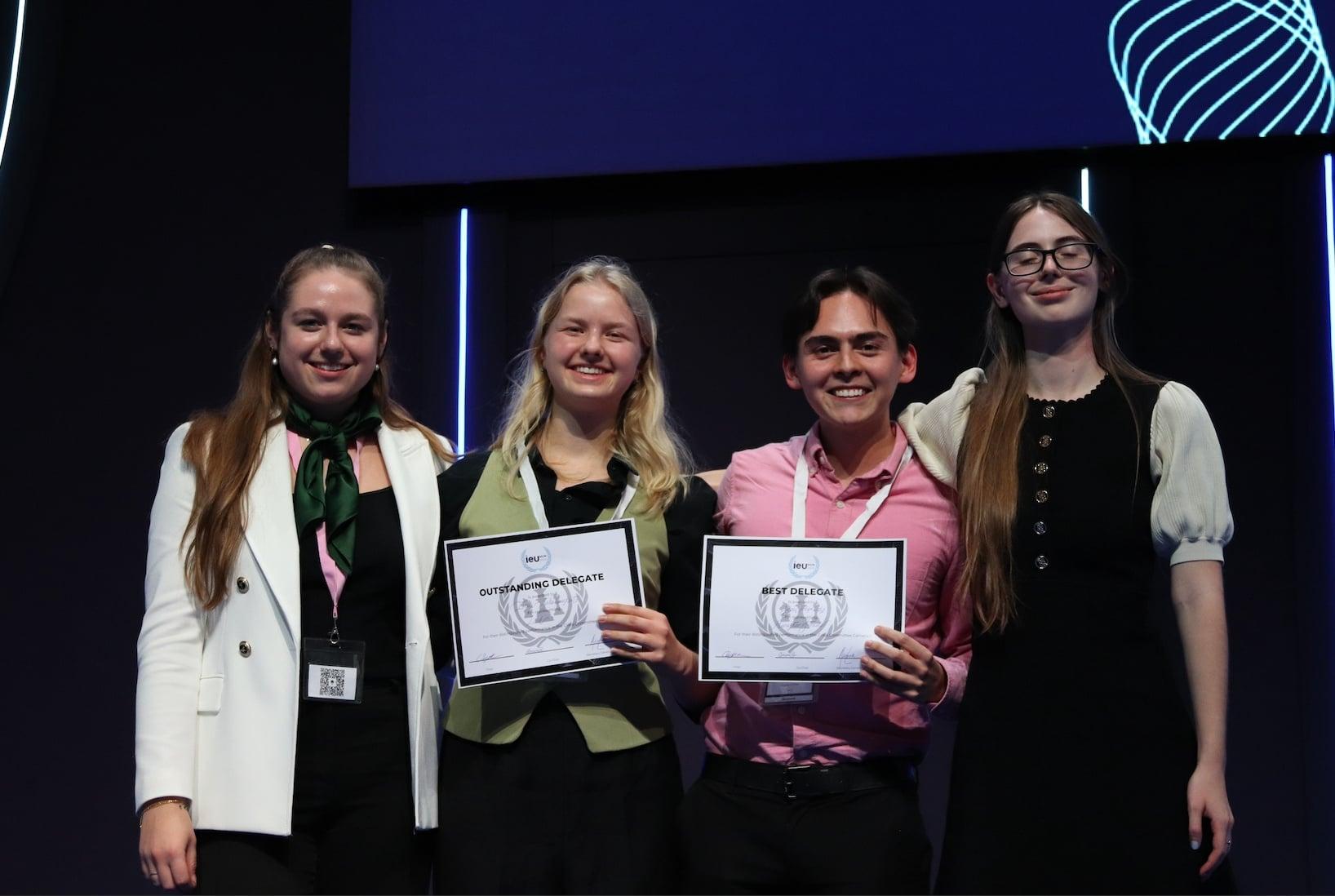 Juan Felipe on stage holding his Best Delegate certificate, beside the other award winners at a Model UN conference.