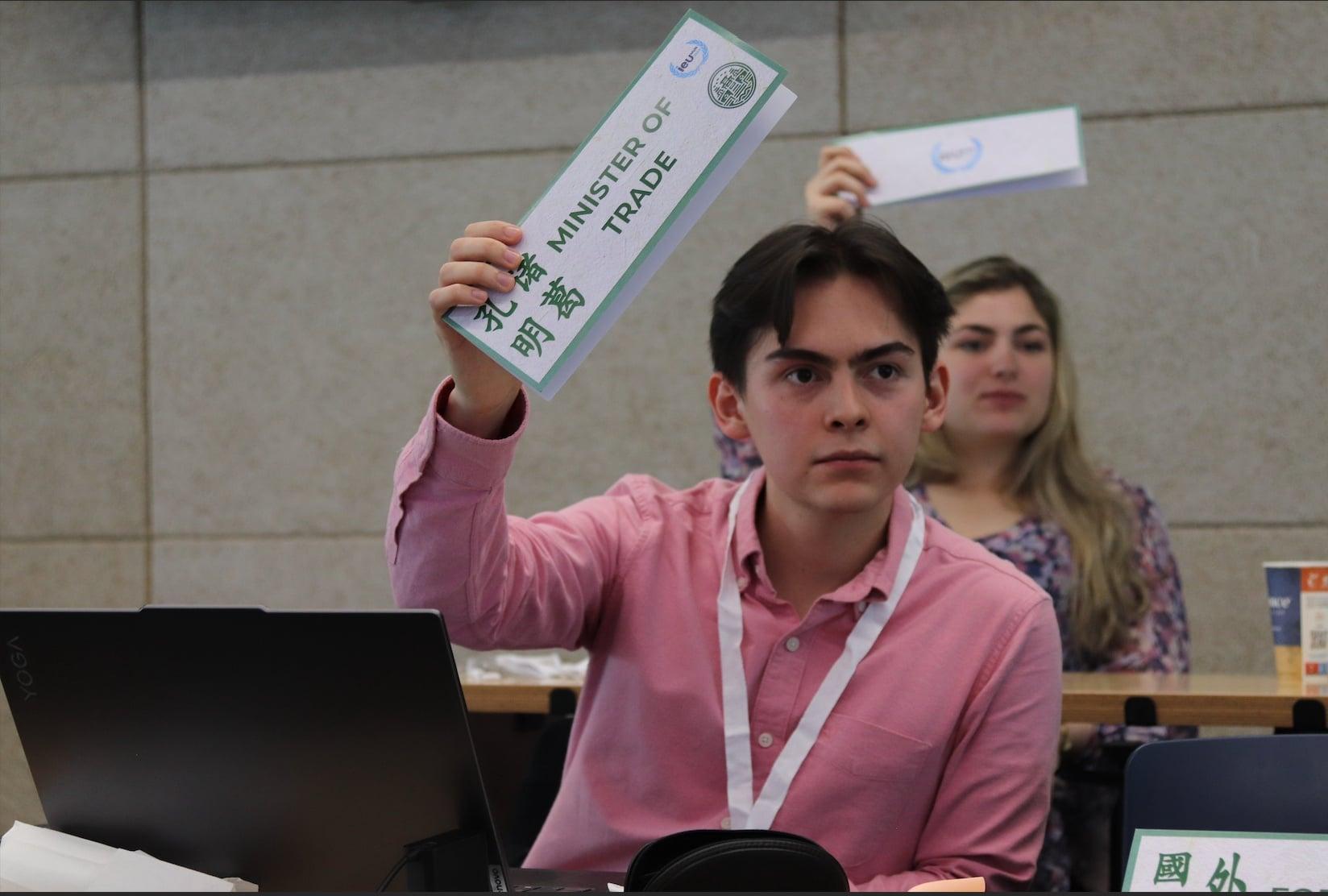 Juan Felipe raising the Minister of Trade placard in a Model UN crisis committee session.